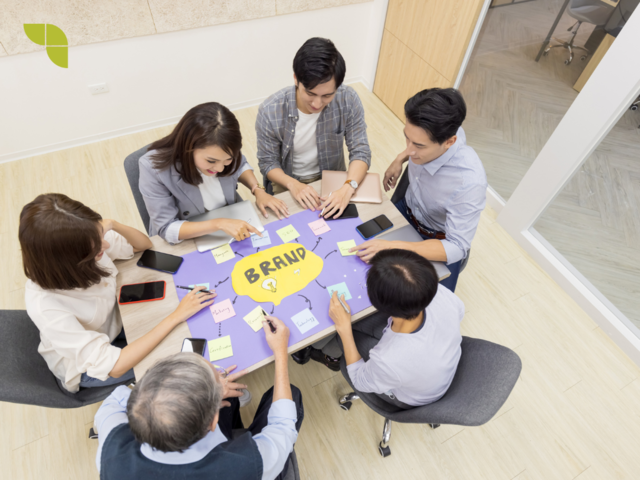 Group of people around a table having a meeting and discussing ideas around branding